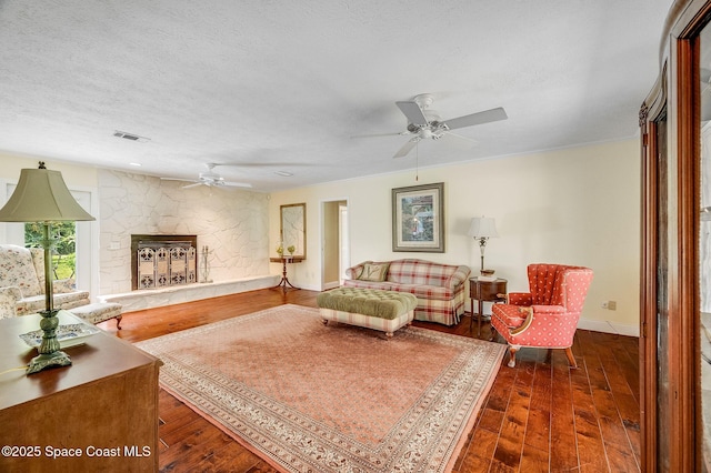 2280 Grove St, Titusville, FL 32796 - living area with a ceiling fan, a textured ceiling, dark wood-style flooring, baseboards, and a stone fireplace