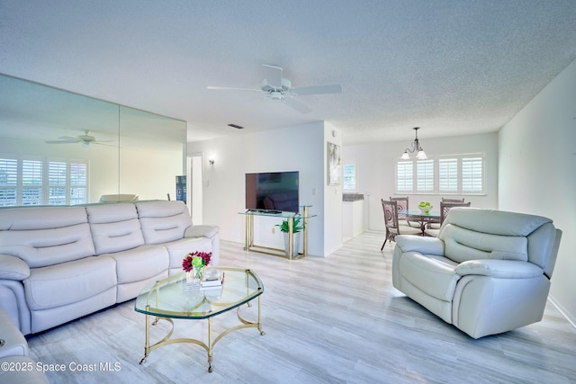 70 Royal Oak Ct Unit 206, Vero Beach, FL 32962 - living room with ceiling fan, light wood-style flooring, baseboards, a textured ceiling, and a chandelier