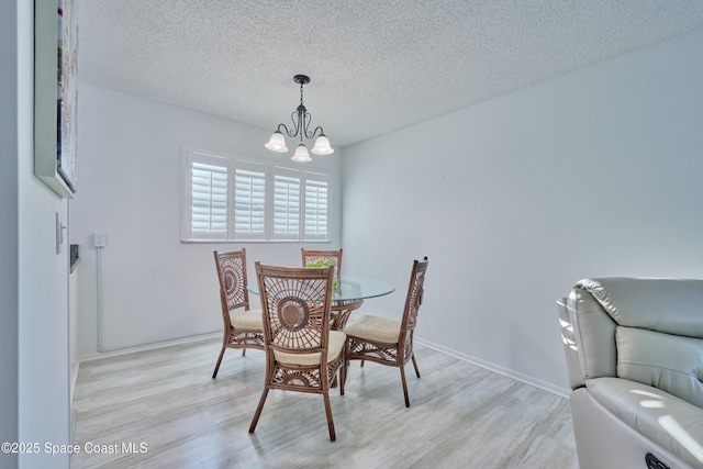 70 Royal Oak Ct Unit 206, Vero Beach, FL 32962 - dining room featuring a chandelier, light wood-style floors, and a textured ceiling
