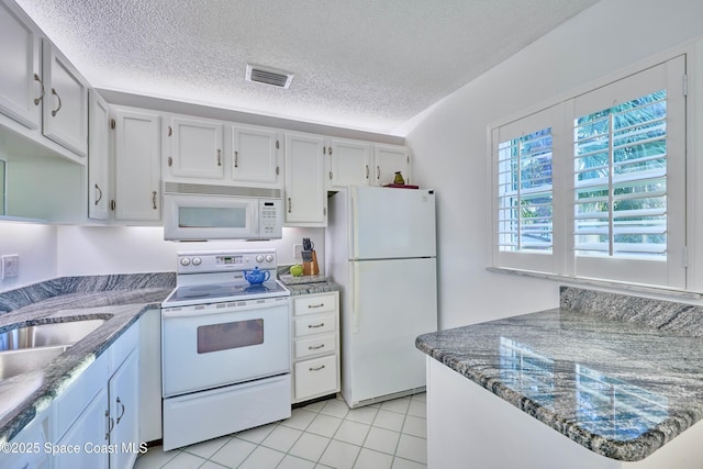 70 Royal Oak Ct Unit 206, Vero Beach, FL 32962 - kitchen with white appliances, a textured ceiling, light tile patterned floors, and dark stone counters
