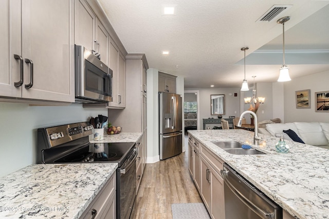 6015 Turtle Beach Ln Unit 204, Cocoa Beach, FL 32931 - kitchen with appliances with stainless steel finishes, a sink, light wood finished floors, light stone counters, and a textured ceiling