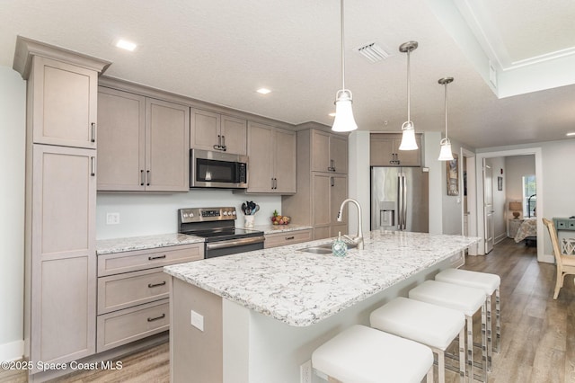 6015 Turtle Beach Ln Unit 204, Cocoa Beach, FL 32931 - kitchen with stainless steel appliances, a sink, light wood-style floors, a kitchen island with sink, and a breakfast bar