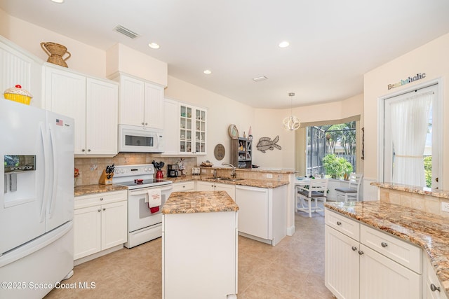 140 Miami Ave, Indialantic, FL 32903 - kitchen featuring white appliances, a peninsula, tasteful backsplash, white cabinets, and light stone counters