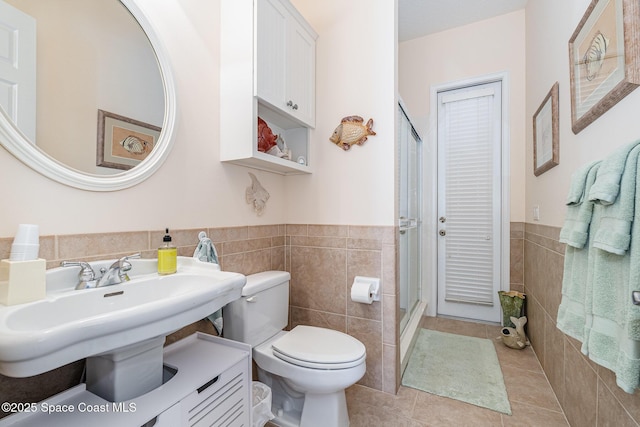 140 Miami Ave, Indialantic, FL 32903 - bathroom featuring tile walls, tile patterned flooring, toilet, wainscoting, and a shower stall
