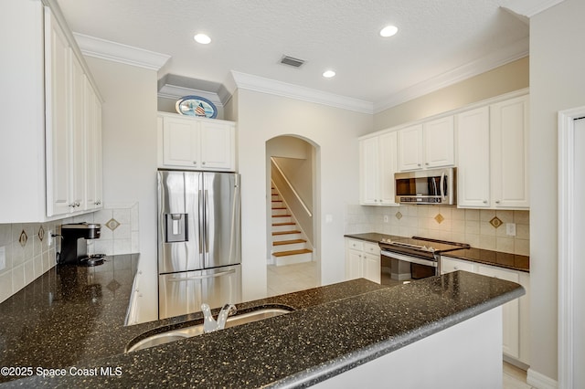 274 Clyde St, Melbourne Beach, FL 32951 - kitchen featuring stainless steel appliances, a sink, dark stone countertops, white cabinetry, and crown molding