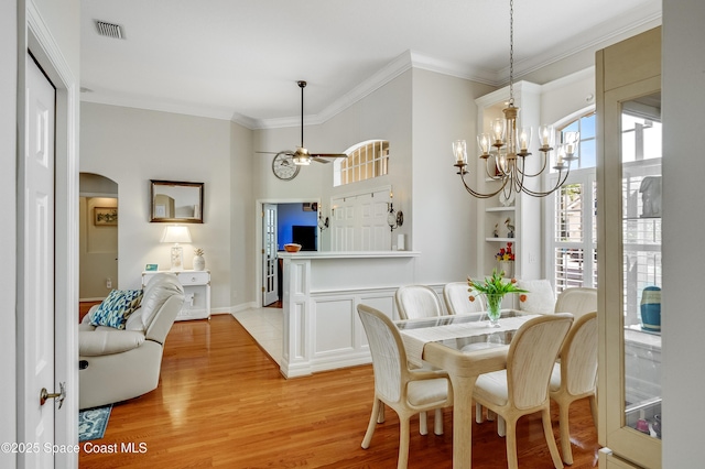 274 Clyde St, Melbourne Beach, FL 32951 - dining space with light wood-style floors, ornamental molding, a ceiling fan, a chandelier, and arched walkways