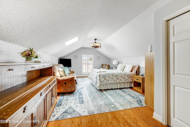 274 Clyde St, Melbourne Beach, FL 32951 - bedroom with a textured ceiling, a skylight, light wood-type flooring, vaulted ceiling, and baseboards
