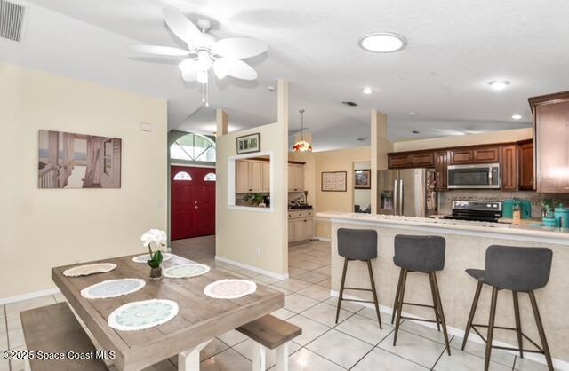 1066 Pennsylvania Ave NE, Palm Bay, FL 32907 - dining space with vaulted ceiling, light tile patterned floors, ceiling fan, baseboards, and recessed lighting