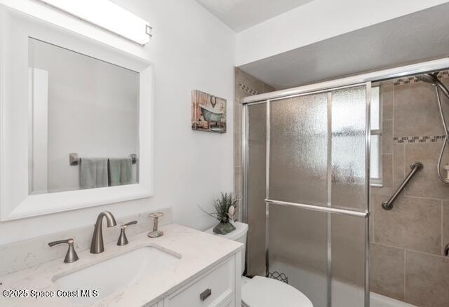 1066 Pennsylvania Ave NE, Palm Bay, FL 32907 - full bathroom with vanity, a shower with shower door, and toilet