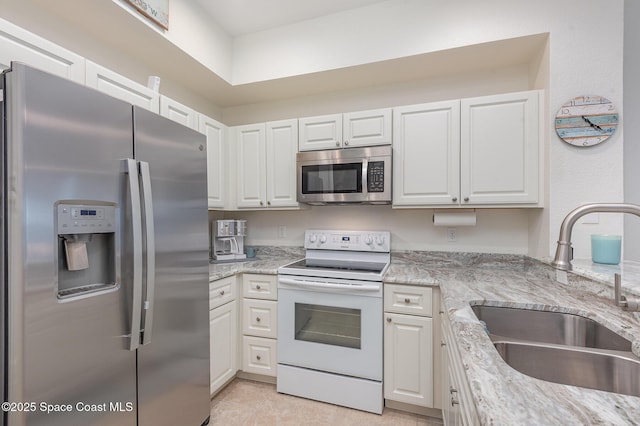115 Turpial Way Unit 104, Melbourne, FL 32901 - kitchen featuring stainless steel appliances, a sink, white cabinetry, and light stone countertops