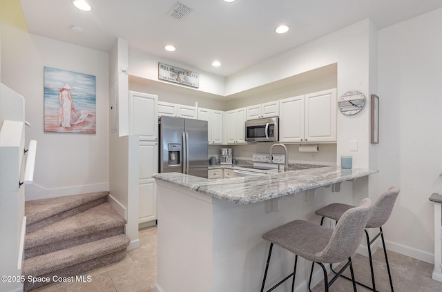 115 Turpial Way Unit 104, Melbourne, FL 32901 - kitchen with appliances with stainless steel finishes, light stone counters, a peninsula, a kitchen breakfast bar, and baseboards