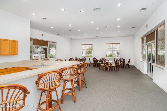 115 Turpial Way Unit 104, Melbourne, FL 32901 - kitchen featuring recessed lighting, light carpet, light countertops, a kitchen bar, and a sink