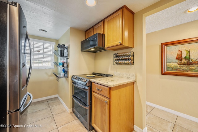 4100 Ocean Beach Blvd Unit 412, Cocoa Beach, FL 32931 - kitchen with appliances with stainless steel finishes, a textured ceiling, light tile patterned floors, brown cabinetry, and baseboards