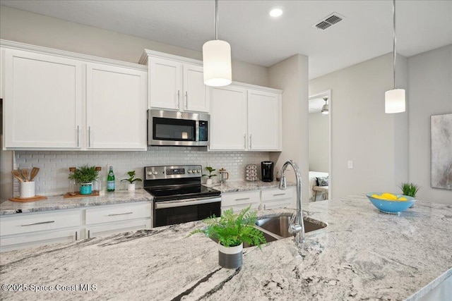 2377 Aquilos Ave SE Unit 46, Palm Bay, FL 32909 - kitchen with stainless steel appliances, a sink, white cabinets, decorative backsplash, and light stone countertops