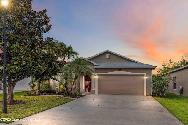 2262 Lune Ct, West Melbourne, FL 32904 - view of front of house featuring stucco siding, driveway, an attached garage, and a lawn
