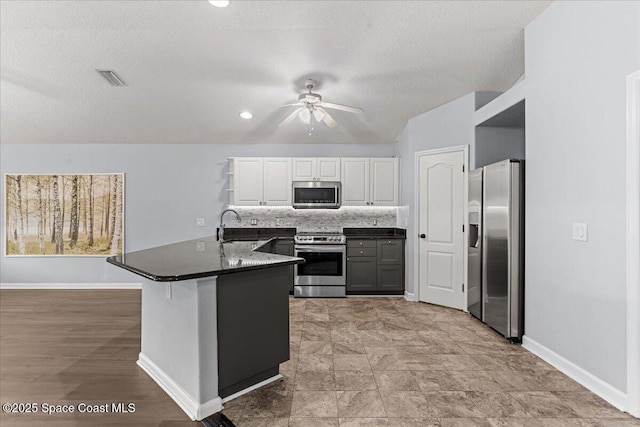 3817 Sunbeam Ct, Merritt Island, FL 32953 - kitchen featuring stainless steel appliances, a peninsula, a ceiling fan, white cabinetry, and baseboards