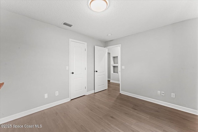 3817 Sunbeam Ct, Merritt Island, FL 32953 - unfurnished bedroom with baseboards, wood finished floors, and a textured ceiling