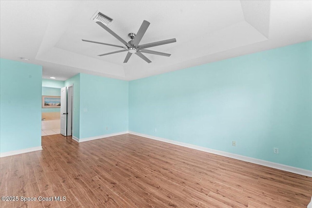 3817 Sunbeam Ct, Merritt Island, FL 32953 - empty room featuring a raised ceiling, wood finished floors, a ceiling fan, and baseboards