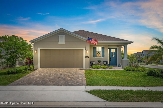 2376 Kamin Dr, Melbourne, FL 32940 - view of front facade with decorative driveway, a yard, a garage, and stucco siding