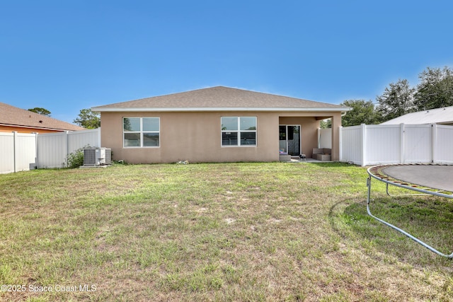 1005 Slocum St NW, Palm Bay, FL 32907 - rear view of house featuring stucco siding, a trampoline, and central AC