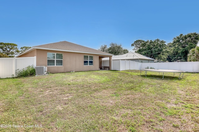 1005 Slocum St NW, Palm Bay, FL 32907 - back of property featuring a trampoline, central air condition unit, and stucco siding
