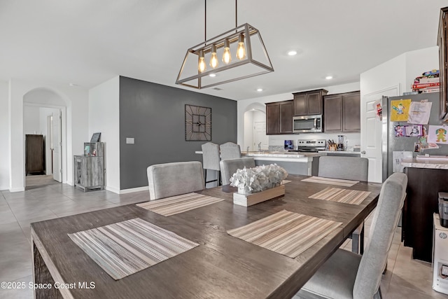 1005 Slocum St NW, Palm Bay, FL 32907 - dining space featuring arched walkways, recessed lighting, light tile patterned floors, and baseboards
