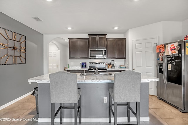 1005 Slocum St NW, Palm Bay, FL 32907 - kitchen with appliances with stainless steel finishes, a sink, a kitchen breakfast bar, dark brown cabinets, and recessed lighting