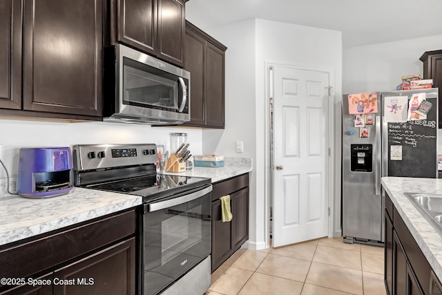 1005 Slocum St NW, Palm Bay, FL 32907 - kitchen featuring appliances with stainless steel finishes, dark brown cabinets, light tile patterned flooring, and light countertops