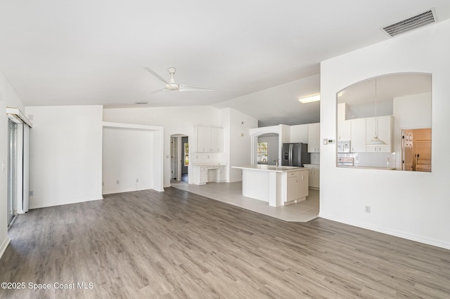 1555 Knoll Ridge Dr, Melbourne, FL 32940 - unfurnished living room featuring vaulted ceiling, ceiling fan, arched walkways, light wood-style flooring, and a sink