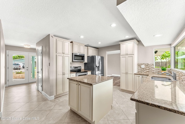 475 Park Ave, Satellite Beach, FL 32937 - kitchen with stainless steel appliances, a sink, cream cabinetry, a textured ceiling, and plenty of natural light