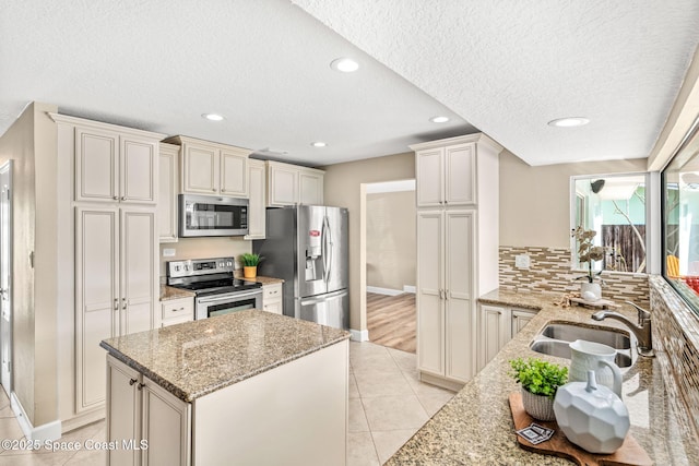 475 Park Ave, Satellite Beach, FL 32937 - kitchen featuring appliances with stainless steel finishes, a sink, baseboards, a textured ceiling, and light stone countertops