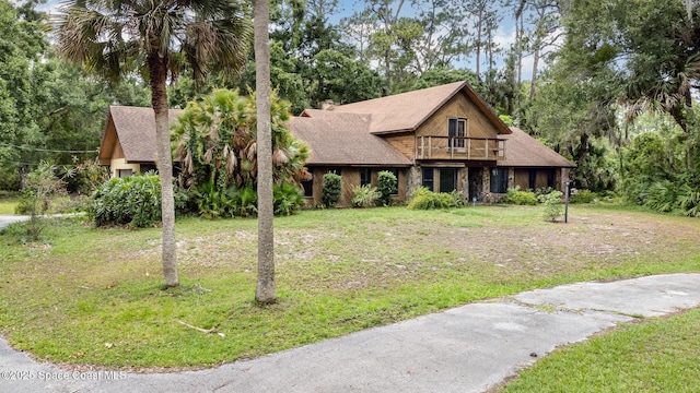 4121 Mustang Rd, Melbourne, FL 32934 - view of front of home featuring a balcony, a front yard, view of scattered trees, and roof with shingles