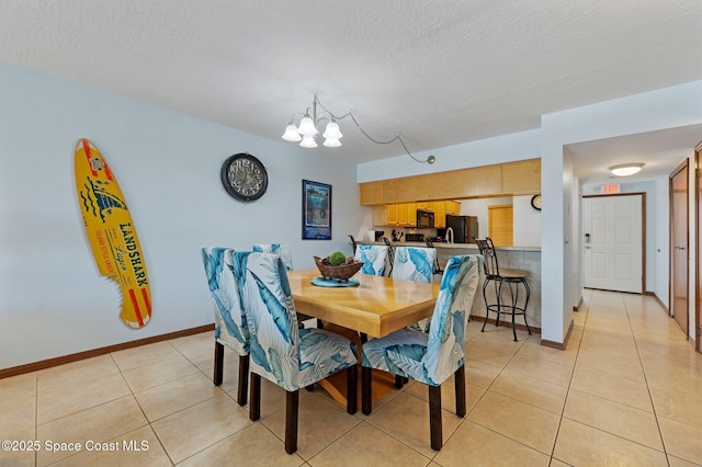 1000 N Atlantic Ave Unit 614, Cocoa Beach, FL 32931 - dining area featuring a chandelier, light tile patterned flooring, baseboards, and a textured ceiling