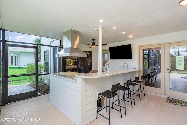 3750 Shady Run Rd, Melbourne, FL 32934 - kitchen with island range hood, a textured ceiling, a ceiling fan, recessed lighting, and a kitchen bar