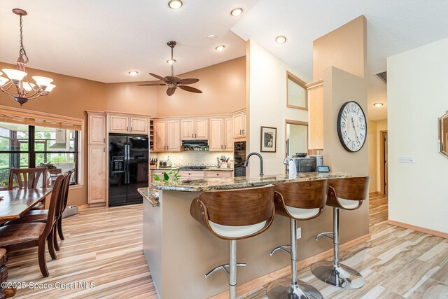 3750 Shady Run Rd, Melbourne, FL 32934 - kitchen featuring black appliances, a peninsula, light stone countertops, light wood-style flooring, and tasteful backsplash