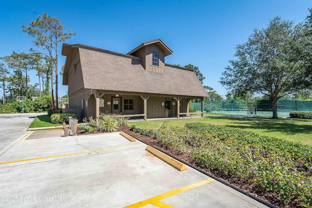 3750 Shady Run Rd, Melbourne, FL 32934 - back of property featuring board and batten siding, uncovered parking, a porch, a shingled roof, and a tennis court