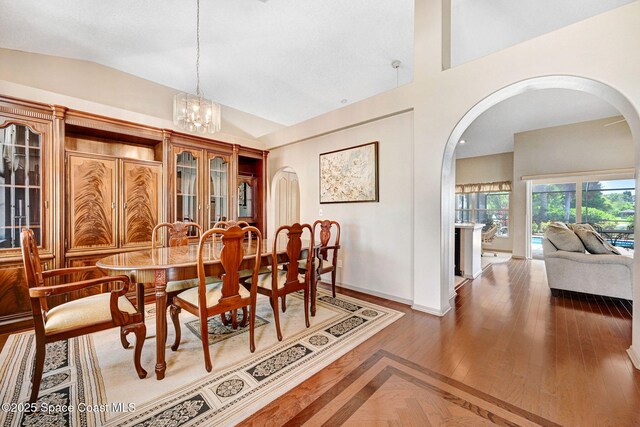 1068 Egret Lake Way, Melbourne, FL 32940 - dining area with arched walkways, baseboards, a chandelier, vaulted ceiling, and wood finished floors