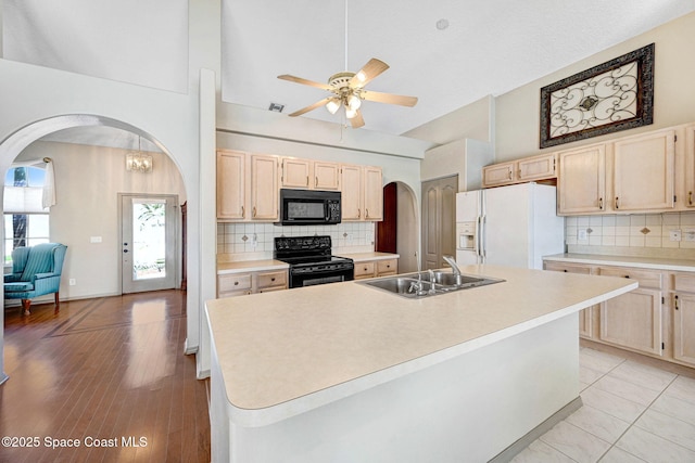 1068 Egret Lake Way, Melbourne, FL 32940 - kitchen with black appliances, arched walkways, a sink, light brown cabinets, and high vaulted ceiling