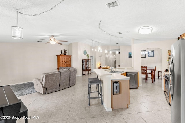 1223 Brumpton Pl, Rockledge, FL 32955 - kitchen featuring appliances with stainless steel finishes, a textured ceiling, a sink, open floor plan, and a breakfast bar area