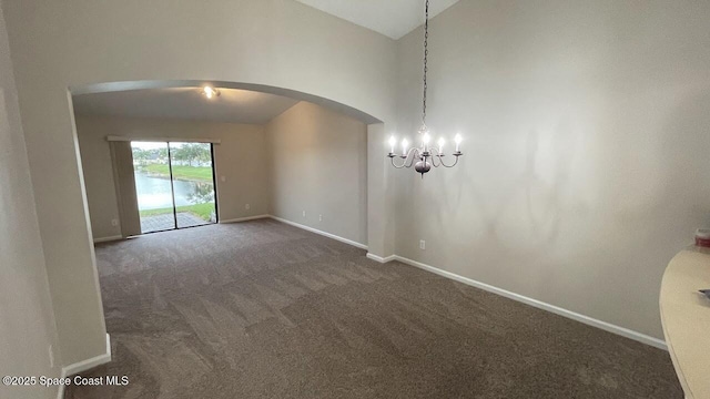 975 Luminary Cir Unit 103, Melbourne, FL 32901 - empty room featuring arched walkways, dark carpet, baseboards, a chandelier, and high vaulted ceiling