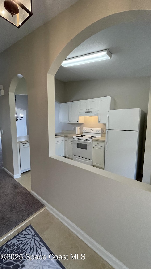 975 Luminary Cir Unit 103, Melbourne, FL 32901 - kitchen featuring white appliances, arched walkways, white cabinetry, light countertops, and under cabinet range hood