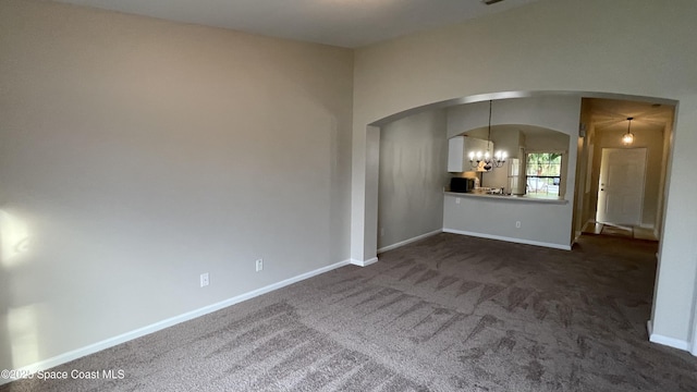 975 Luminary Cir Unit 103, Melbourne, FL 32901 - spare room with arched walkways, a chandelier, dark carpet, and baseboards