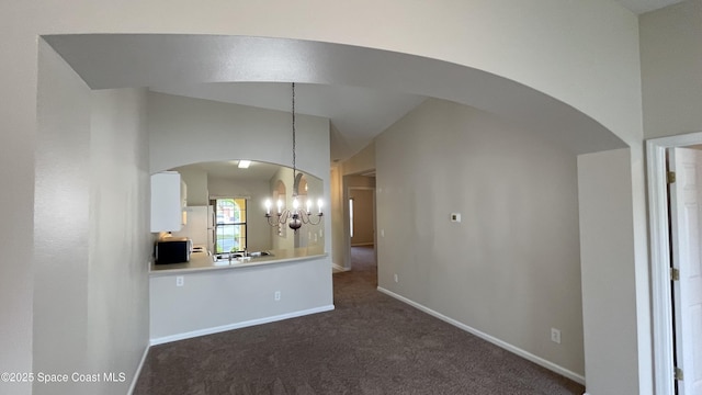 975 Luminary Cir Unit 103, Melbourne, FL 32901 - unfurnished living room with arched walkways, a chandelier, dark carpet, baseboards, and vaulted ceiling