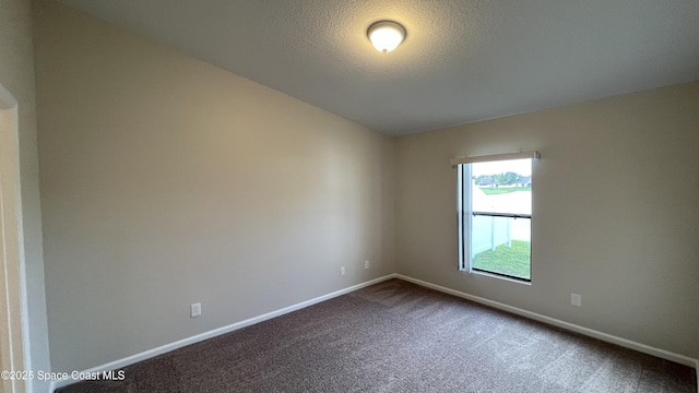 975 Luminary Cir Unit 103, Melbourne, FL 32901 - spare room featuring baseboards, dark carpet, and a textured ceiling