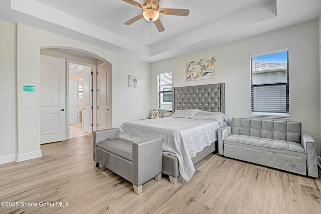 8212 Paragrass Ave, Melbourne, FL 32940 - bedroom featuring a tray ceiling, light wood-style floors, arched walkways, and multiple windows