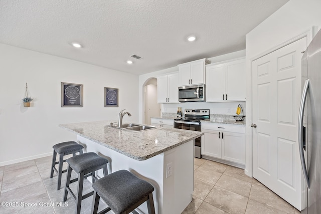 637 Old Country Rd SE, Palm Bay, FL 32909 - kitchen with stainless steel appliances, a sink, arched walkways, a breakfast bar, and a kitchen island with sink