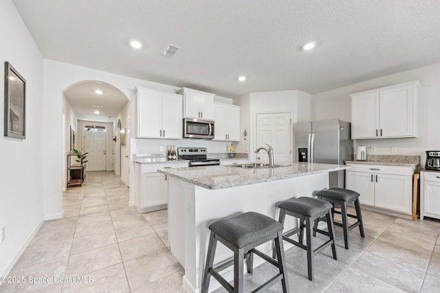 637 Old Country Rd SE, Palm Bay, FL 32909 - kitchen featuring stainless steel appliances, a sink, a kitchen breakfast bar, white cabinetry, and a kitchen island with sink