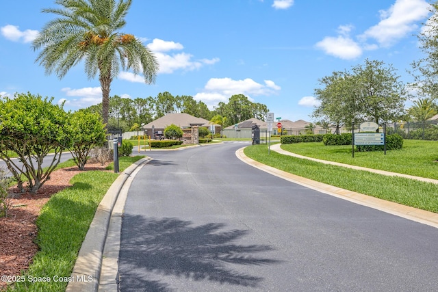637 Old Country Rd SE, Palm Bay, FL 32909 - view of asphalt road with curbs, traffic signs, a residential view, and a gated entry