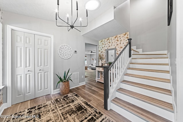 3203 Wind Song Ct, Melbourne, FL 32934 - foyer entrance featuring stairs, a chandelier, wood finished floors, and baseboards