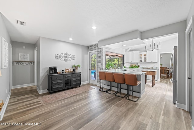3203 Wind Song Ct, Melbourne, FL 32934 - kitchen with a kitchen breakfast bar, white cabinets, light wood-style floors, a sink, and recessed lighting